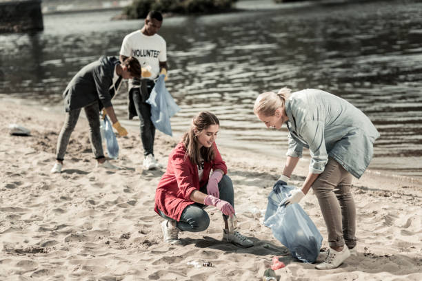 istock Caring blonde-haired teacher helping her students volunteering at the beach 1050789410