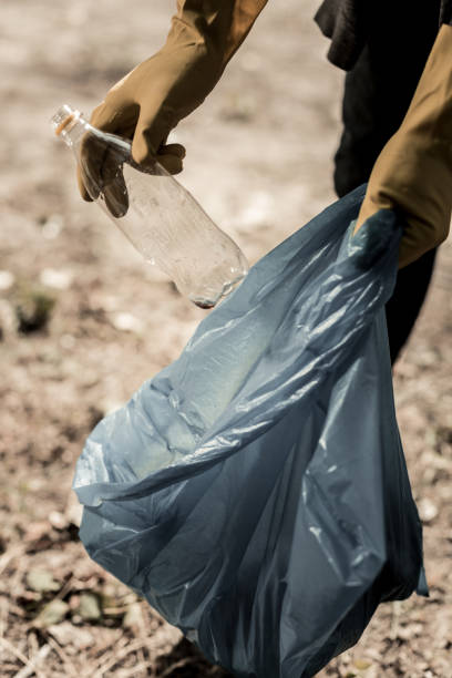 istock Man volunteering in forest wearing yellow gloves while gathering empty bottles 1050790140
