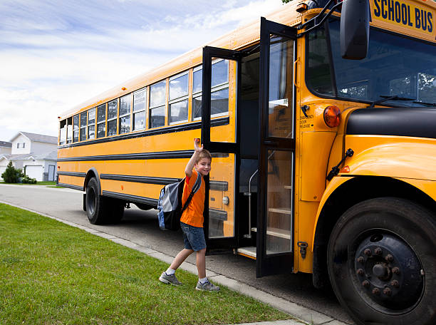 Young boy and yellow school bus stock photo