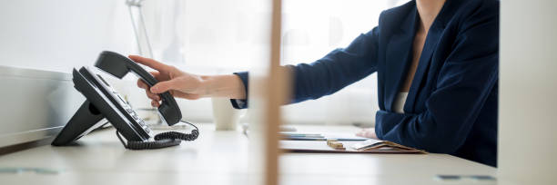 Businesswoman or picking or hanging up  handset View through an office partition of a businesswoman or secretary picking or hanging up telephone handset. answering stock pictures, royalty-free photos & images