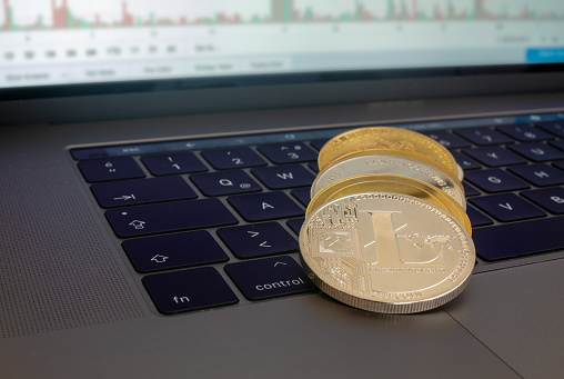 Denizli, Turkey - 6 October 2018: Golden physical Bitcoin, Ethereum and Litecoins ,Ripple  on notebook keyboard with a blurry background of bitcoin chart on the screen.Cryptocurrency market coins with notebook concept concept.