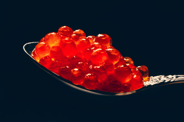 istock Red caviar in spoon on black background, macro photo 1050817616