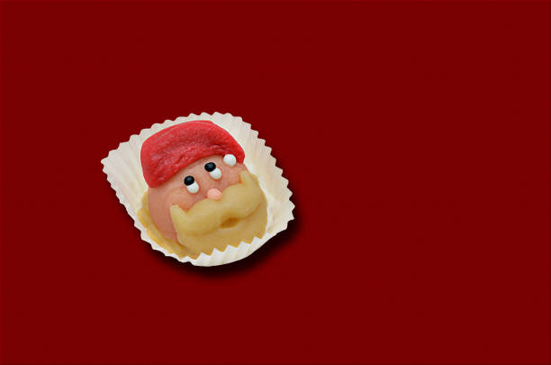 head of Santa Claus  marzipan praline, isolated on red background, close up, flat lay, copy space