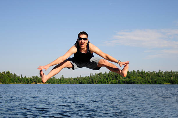 istock Young man jumps doing splits touching toes at the lake. 105082959