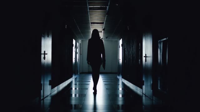 Silhouette of business woman walking along the corridor.