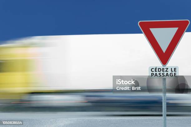 Give Way Yield French Cédez Le Passage Road Sign Motion Blurred Truck Vehicle Traffic Background White Signage Triangle Red Frame Regulatory Warning Metallic Pole Post Blue Summer Sky Panneau Signalisation Cédezlepassage France Stock Photo - Download Image Now