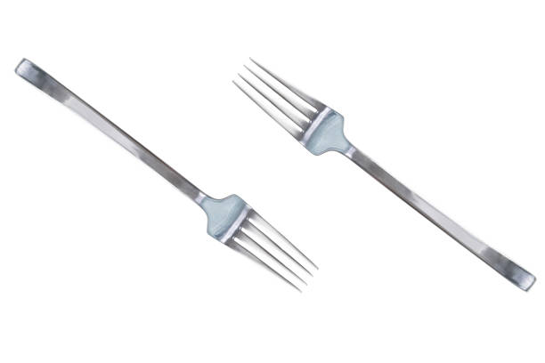 Silver knife floating across a silver fork, white background