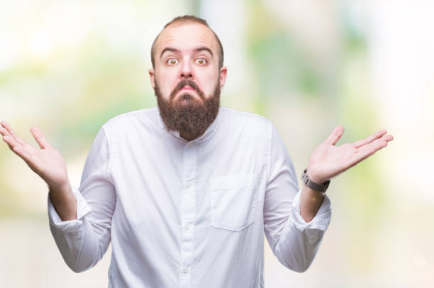 istock Young caucasian hipster man over isolated background clueless and confused expression with arms and hands raised. Doubt concept. 1050839074