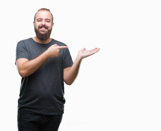 istock Young caucasian hipster man over isolated background amazed and smiling to the camera while presenting with hand and pointing with finger. 1050839288
