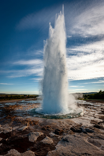 The famous Icelandic Strokkur Geyser erupting hot water and steam against sun and blue summer sky. Haukadalur, Iceland, Europe