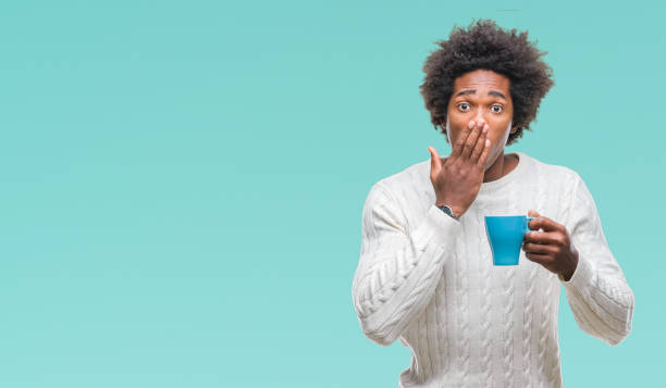 Afro american man drinking cup of coffee over isolated background cover mouth with hand shocked with shame for mistake, expression of fear, scared in silence, secret concept Afro american man drinking cup of coffee over isolated background cover mouth with hand shocked with shame for mistake, expression of fear, scared in silence, secret concept bad coffee stock pictures, royalty-free photos & images