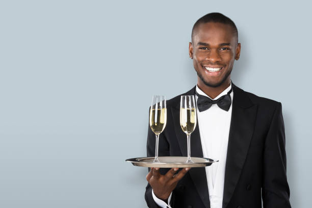 улыбающийся официант холдинг шампанское напиток - waiter butler champagne tray �стоковые фото и изображения