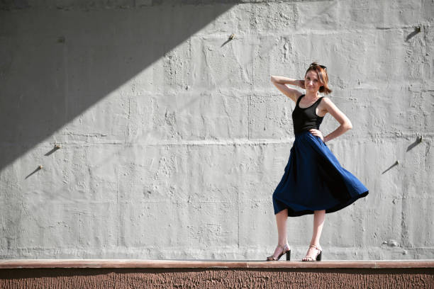 istock young girl posing against a concrete wall, dressed in black, hard light and shadows 1050851402