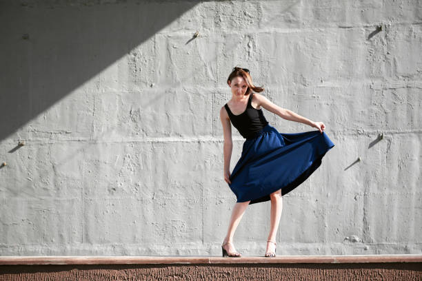 istock young girl posing against a concrete wall, dressed in black, hard light and shadows 1050851436