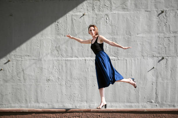 istock young girl posing against a concrete wall, dressed in black, hard light and shadows 1050851472