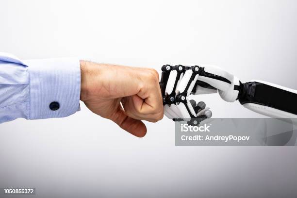 Human Hand And Robot Making Fist Bump Stock Photo - Download Image Now - Robot, People, Artificial Intelligence