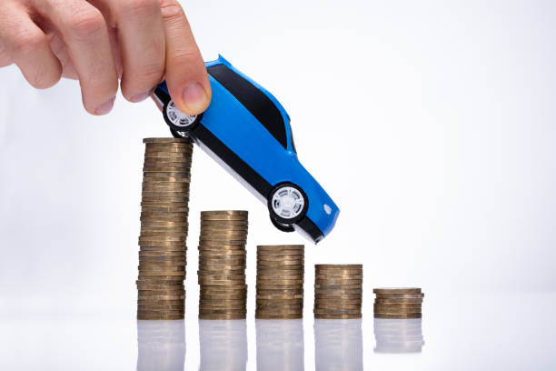 istock Person's Hand Driving Car On Decreasing Stacked Coins 1050855444
