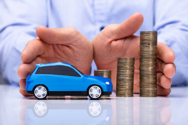 istock Man Protecting Blue Car And Stacked Coins 1050855466