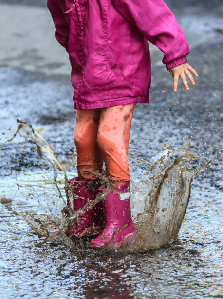 istock Child outdoor jump into puddle in boot after rain 1050859558