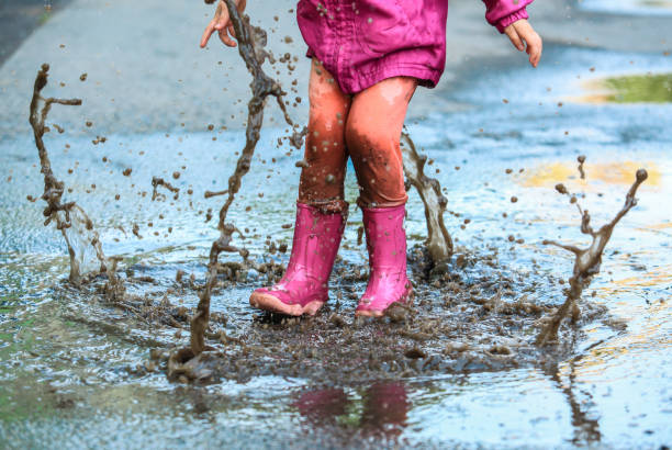 istock Child outdoor jump into puddle in boot after rain 1050859598
