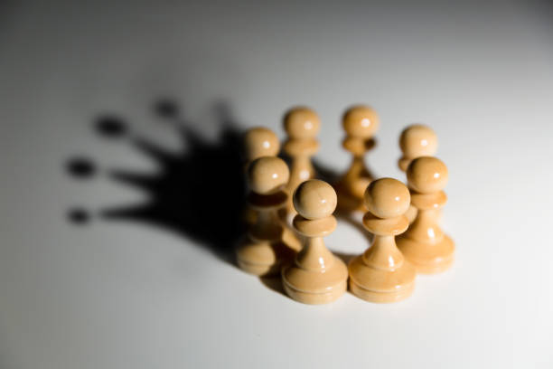 istock Pawns rounded in circle with a crown in shadow. Teamwork and leadership concept. 1050862760