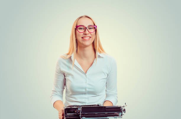 mujer sonriente con máquina de escribir antigua - typewriter retro revival old fashioned obsolete fotografías e imágenes de stock