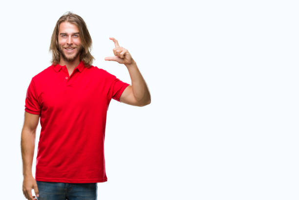 istock Young handsome man with long hair over isolated background smiling and confident gesturing with hand doing size sign with fingers while looking and the camera. Measure concept. 1050877468