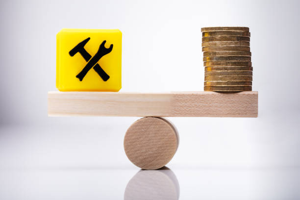 Under Construction Icon Block And Coins Balancing On Seesaw
