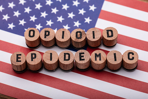 Elevated View Of Opioid Epidemic Text On Wooden Cork Over American Flag