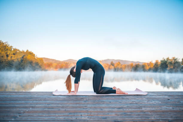 Shot of young woman doing yoga in nature on a misty morning in Ljubljana, Slovenia. Foggy lake is in the back.