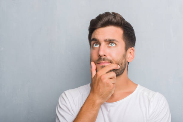 istock Handsome young man over grey grunge wall serious face thinking about question, very confused idea 1050889304
