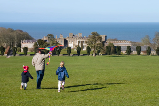A dad and 2 kids flying a kite at Ardgillan Castle on a sunny winters day. Ardgillan is in Skerries, just outside Dublin and looks over the se. It offers a wonderful playground for kids, as well as beautiful gardens and a coffee shop.