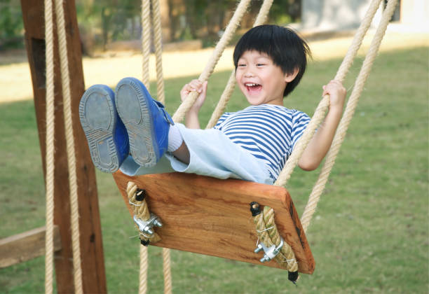 Happy little asian boy laughing and swinging on a swing stock photo