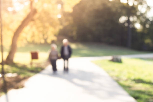 Defocused couple walking in public park. Blurry focus scene