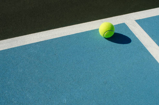 tennisbal berust op blauwe tennisbaan - tennis stockfoto's en -beelden
