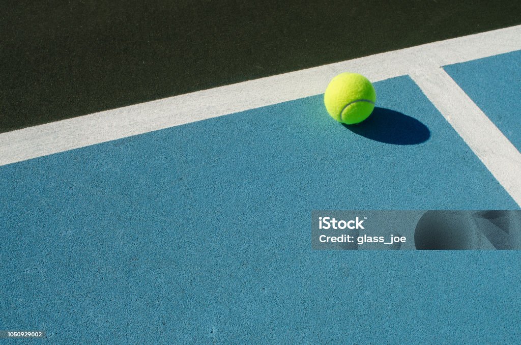 Tennis ball rests on blue tennis court abstract image of a court sport Tennis Stock Photo