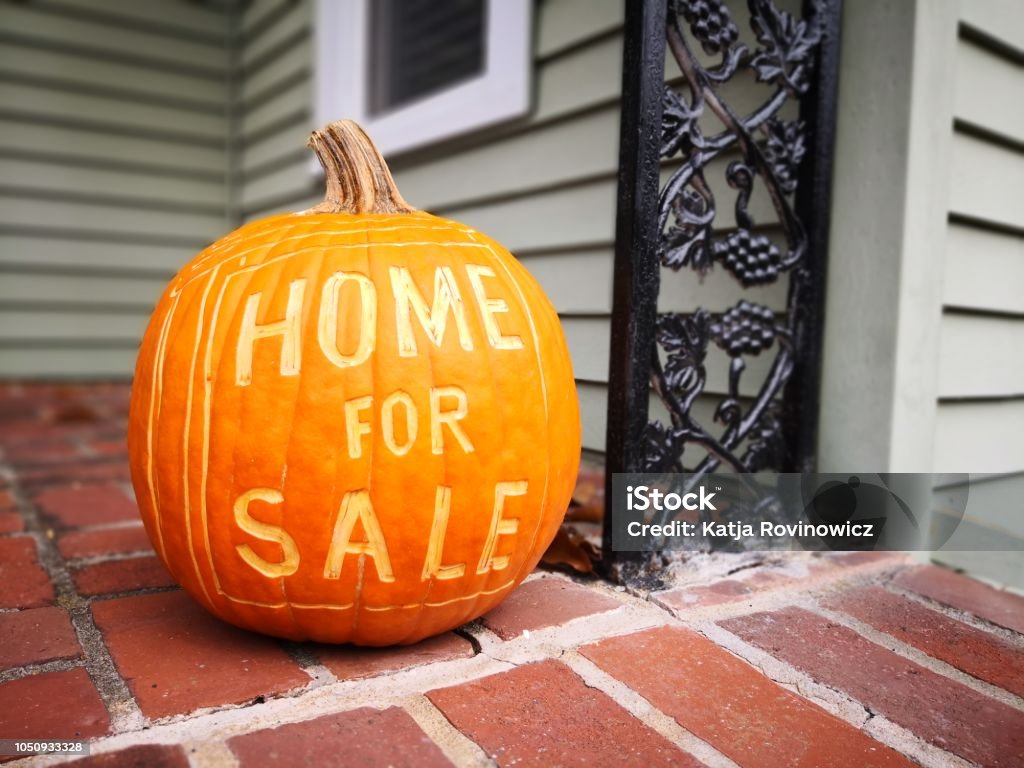 Home For Sale Sign - Fall Open House showing during fall time using a pumpkin carved with a for sale sign. Autumn Stock Photo