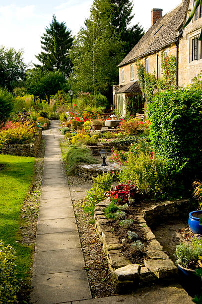 A gravel path through a herbaceous border in an English walled 'secret' garden