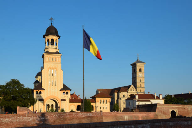 istock Orthodox Reunification Cathedral and Catholic St. Michael's Cathedral, with Romanian flag. Alba Iulia in Transylvania, Romania 1050941956