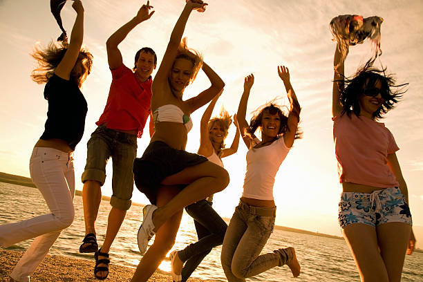 Young woman tossing her hair during a dance on a party at the beach. There are people in the background.