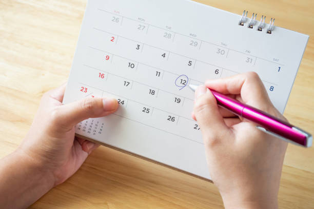 istock calendar page with female hand holding pen on desk table 1050964266