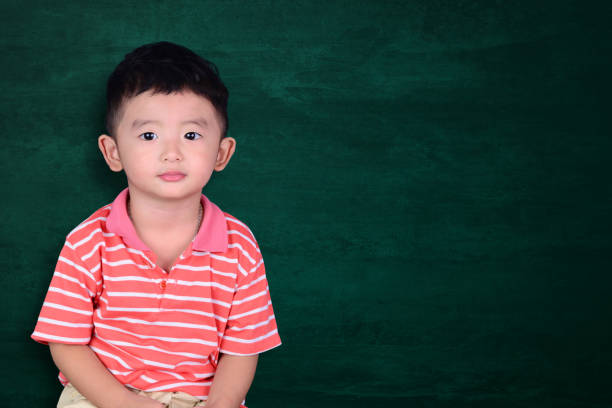 istock Happy Asian kid smiling on empty green chalkboard with copy space for add text or word, education and back to school concept. 1050965046