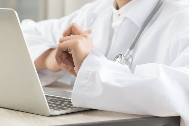 istock Asian Female doctor hands holding pen using tablet computer with gown suite wearing Stethoscope on neck for seaching information treating patients waiting for patient examine at hospital 1050970722