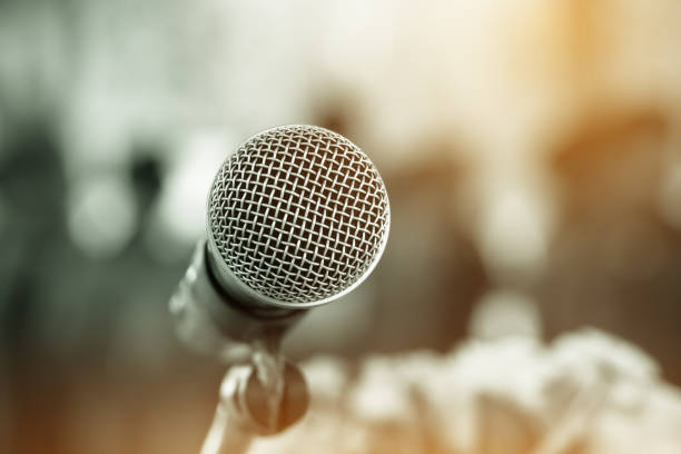 istock Microphone on abstract blurred conference hall prepare for speaker on stage in seminar room. lecture to audience university with bokeh background. Business meeting or education teaching image 1050973106
