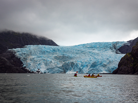 A view of Holgate Glacier in Kenai Fjords National Park, Alaska, with kayakers in the water.