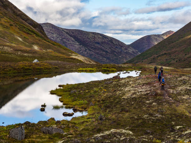 Backpackers on Valley Trail in Autumn Tundra, Mountain Tarn, Chugach State Park, Alaska A group of backpackers hiking along a footpath past a mountain tarn, through autumn tundra in a mountain valley in Chugach State Park, Alaska. chugach mountains photos stock pictures, royalty-free photos & images