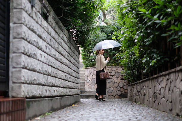 Woman walking on alleyway of traditional old town of Kagurazaka, Tokyo in a rainy day Woman walking in traditional old town of Kagurazaka, Tokyo, in a rainy day low angle street japan stock pictures, royalty-free photos & images