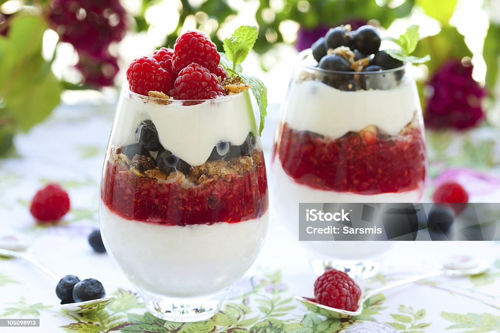 raspberry and blueberry parfait raspberry and blueberry parfait with cream and granola. Glass - Material Stock Photo