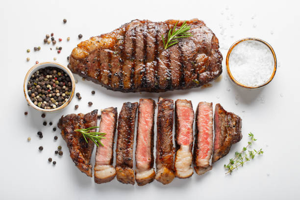 due bistecche di manzo marmorate alla griglia striploin con spezie isolate su sfondo bianco, vista dall'alto - bistecca di manzo foto e immagini stock