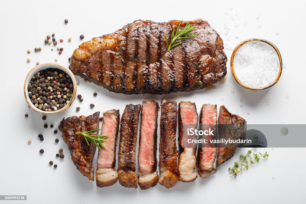 Two grilled marbled beef steaks striploin with spices isolated on white background, top view Two grilled marbled beef steaks striploin with spices isolated on white background, top view. Steak Stock Photo